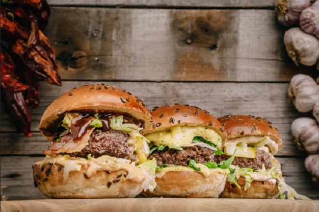 Trois burgers alignés avec du fromage fondant sur les steaks appétissants.