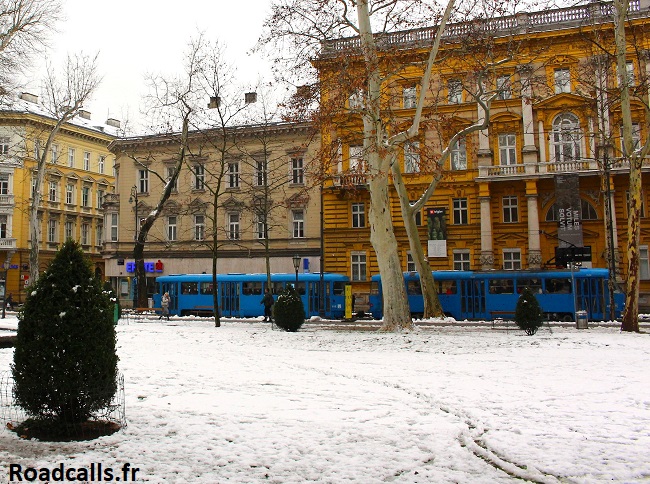 un tram bleu longeant le parc Zrinjevac sous la neige, à Zagreb