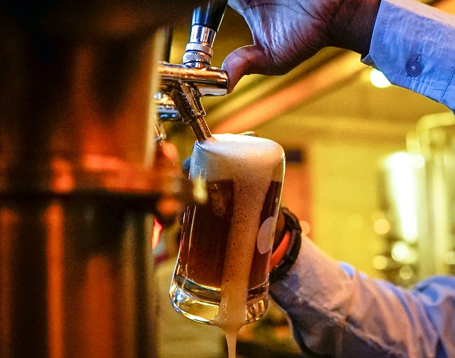 Gros plan sur une pinte de bière moussante en train d'être servie.