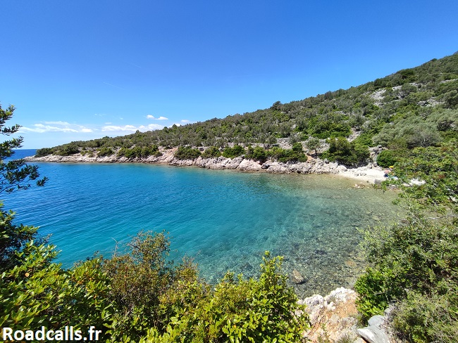 Vu plongeante sur une crique paradisiaque de l'île de Cres, en Croatie, avec ses eaux turquoises, son ciel bleu et sa végétation verdoyante.