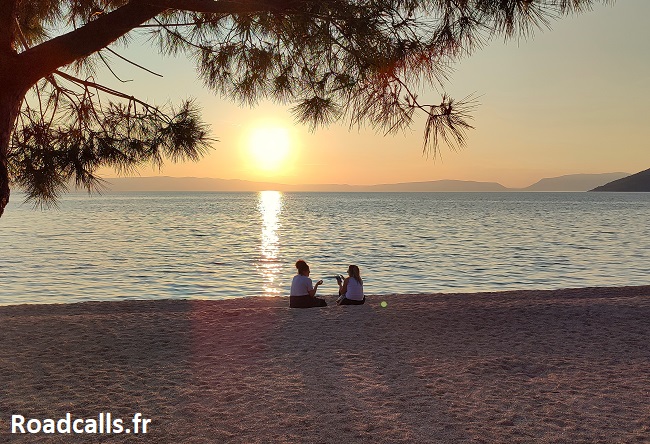 Deux jeunes femmes regardent le coucher de soleil sur la plage de Cres, île de Croatie